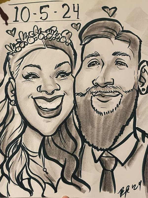 A close up of a caricature of a bride and groom. They are smiling with the wife looking at the husband and hearts floating above them. The date of their wedding is written largely in the corner. Drawn at the Nevermore Station in downtown Indianapolis.